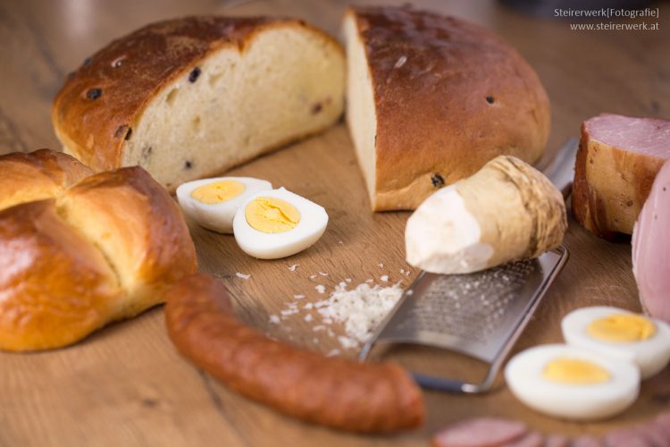 Zutaten für die Osterjause mit Osterbrot, Pinze, Eier, Schinken, Würstel und Kren