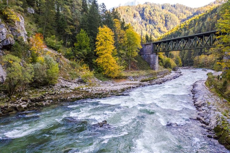 Die Enns fließt im Gesäuse unter eine Eisenbahnbrücke